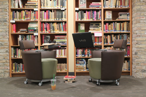 two workstations in front of bookcases at the library