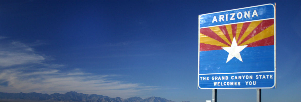 A sign along the highway proclaims Arizona, The Grand Canyon State, Welcomes You