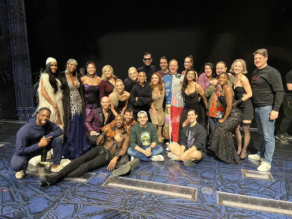 A crowd of about two dozen people pose onstage, Ryan Worsing in the middle, wearing the Robe.