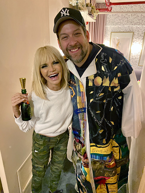 Kober smiles in the Robe next to Kristin Chenoweth, who holds a bottle of champagne.