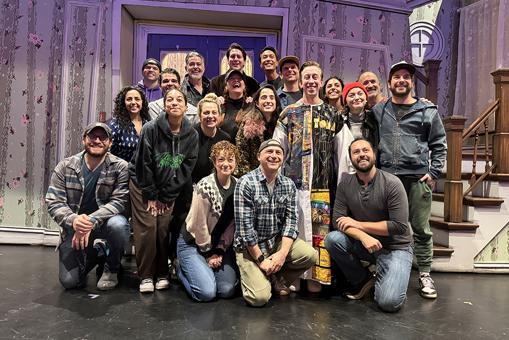 Breslin poses in the Robe onstage, surrounded by about 19 castmates.