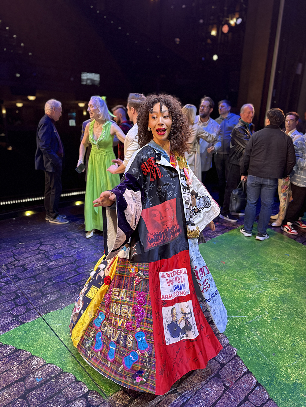 Afra Hines poses onstage in the Robe with people visible behind her.
